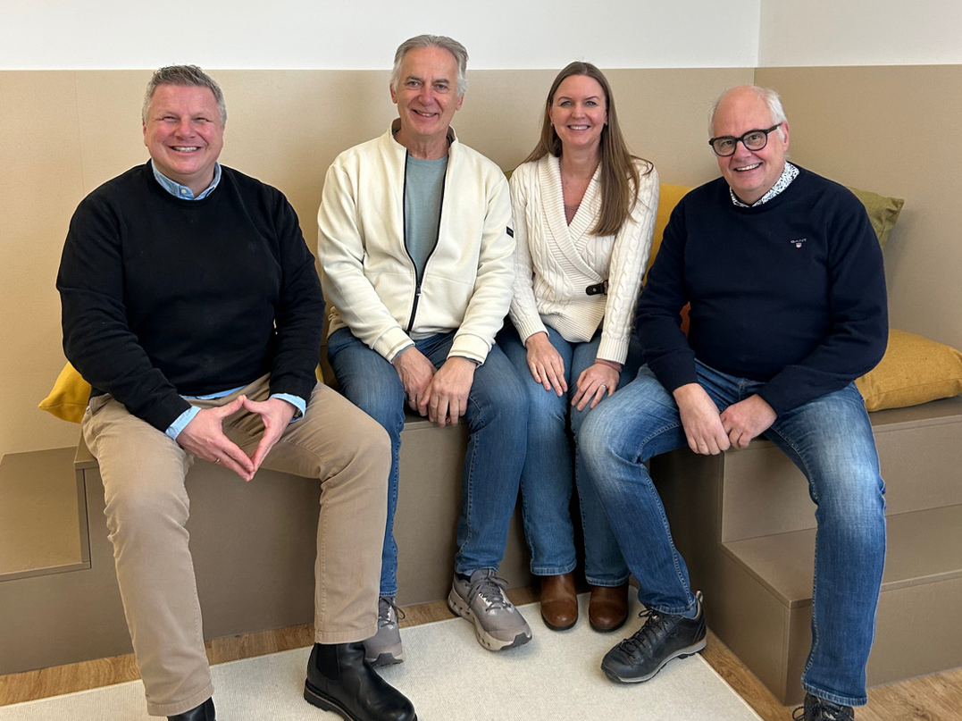 Bild mit den vier beteiligten Personen die auf einer Bank sitzen